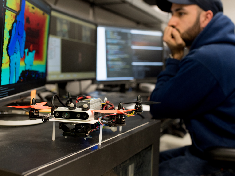 photos of student working in lab on computer next to drone