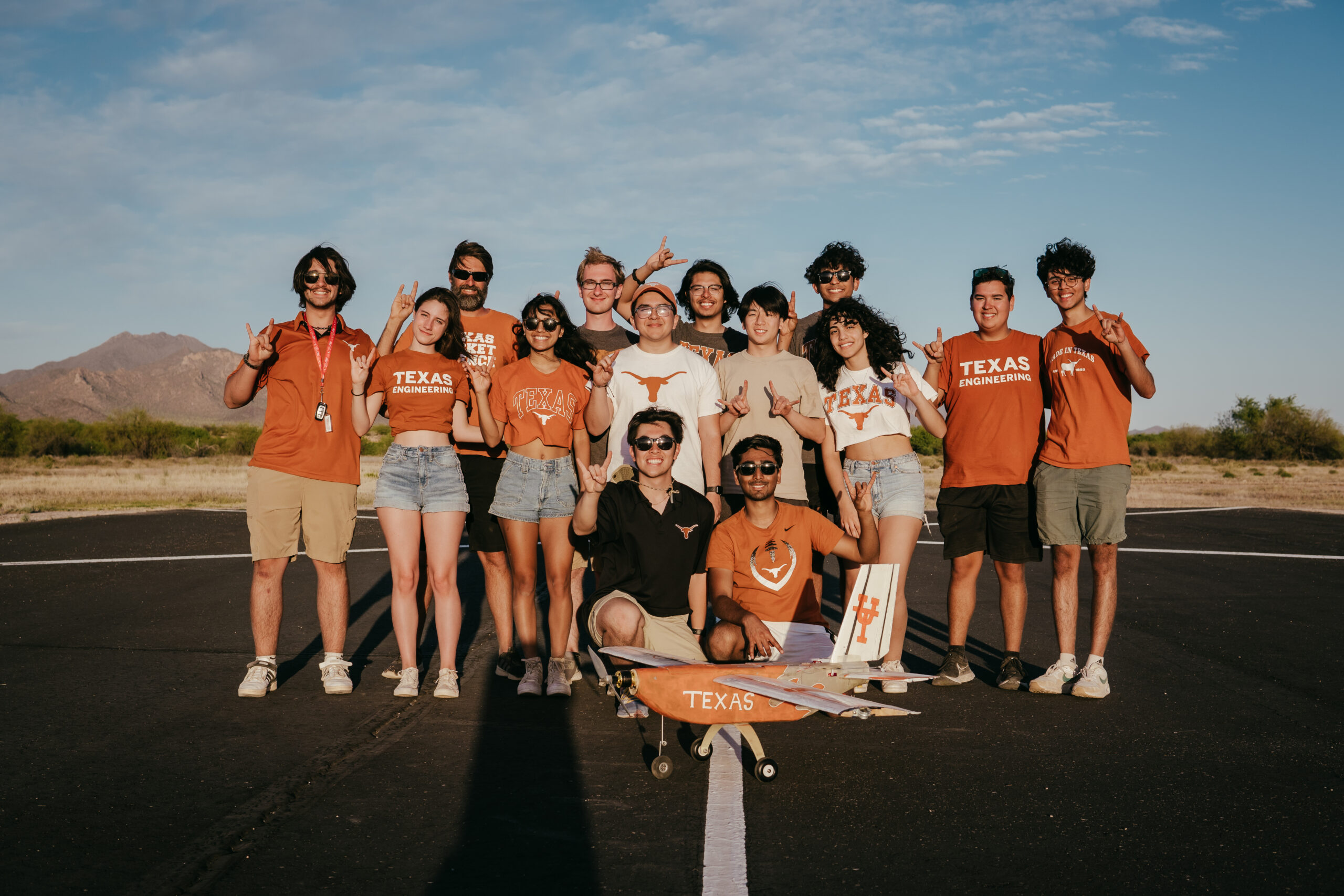 The UT Design Build Fly team posing on airplane landing strip with airplane prototype.