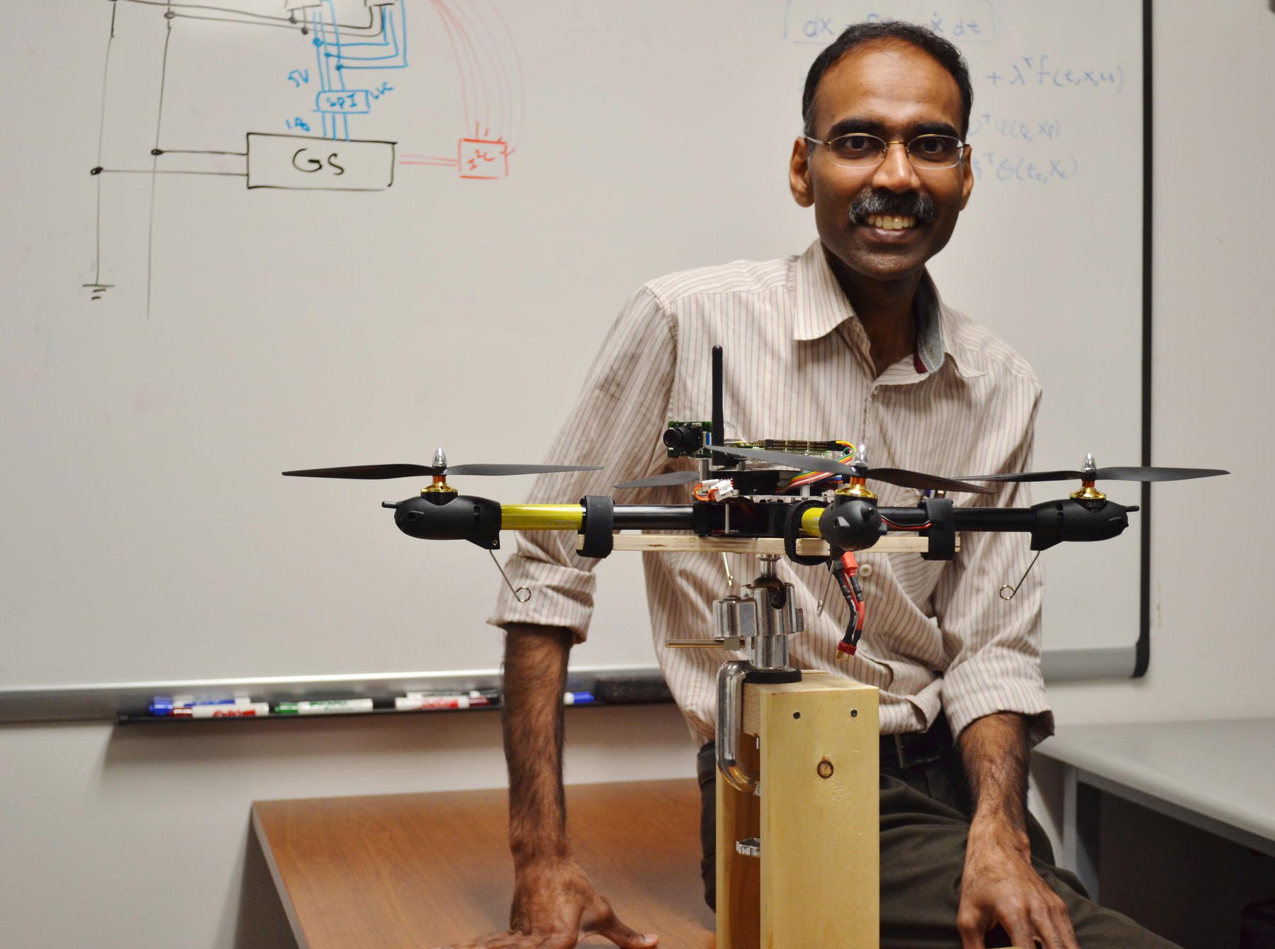 Maruthi Akella smiling next to quadcopter model