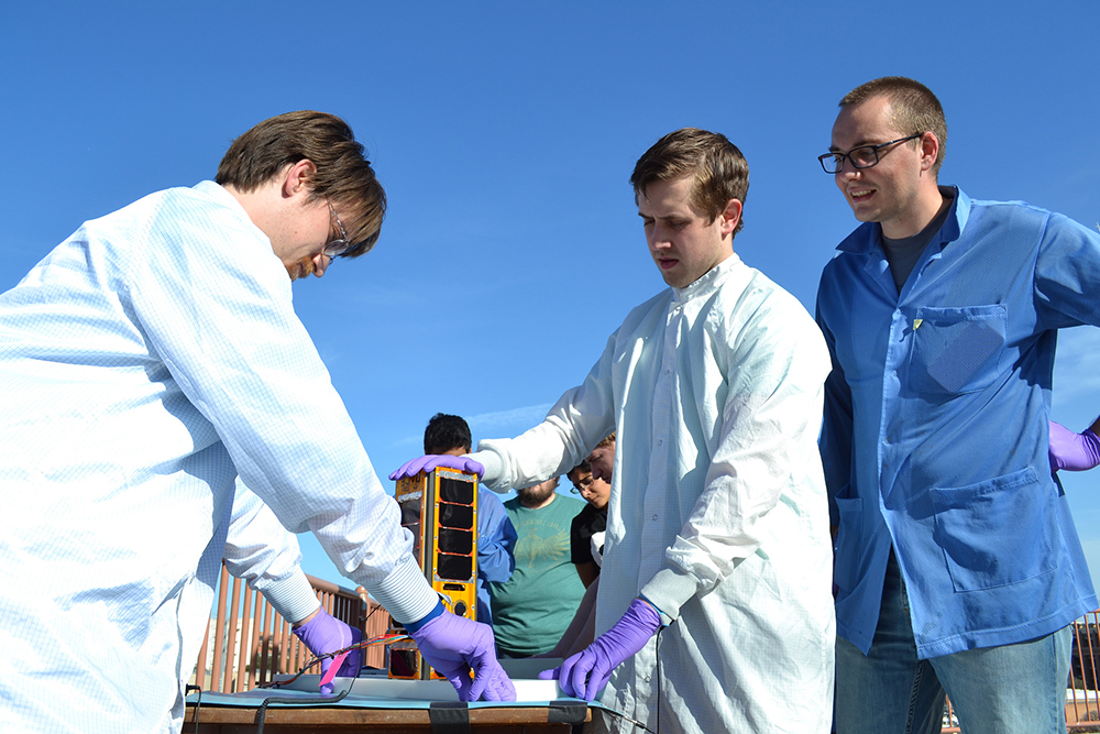 Texas Spacecraft Lab students preparing for race while wearing lab coats.