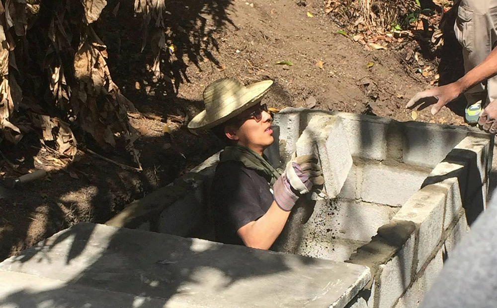 Ruifei Wang handing up cement blocks from a hole.
