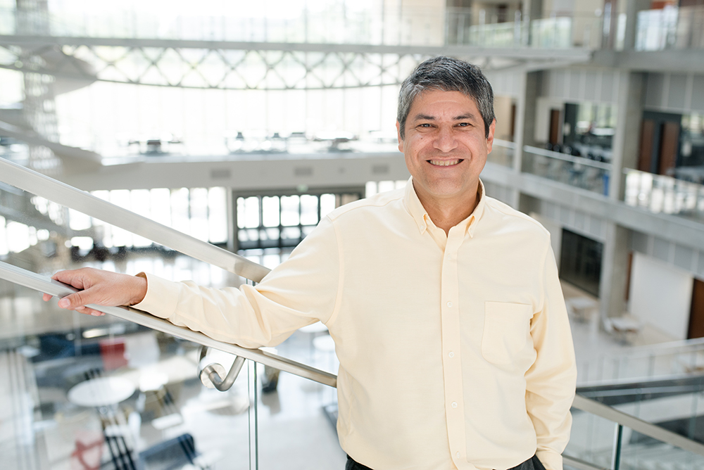 Texas Engineer Noel Clemens smiling in the EER building at the top of the staircase.