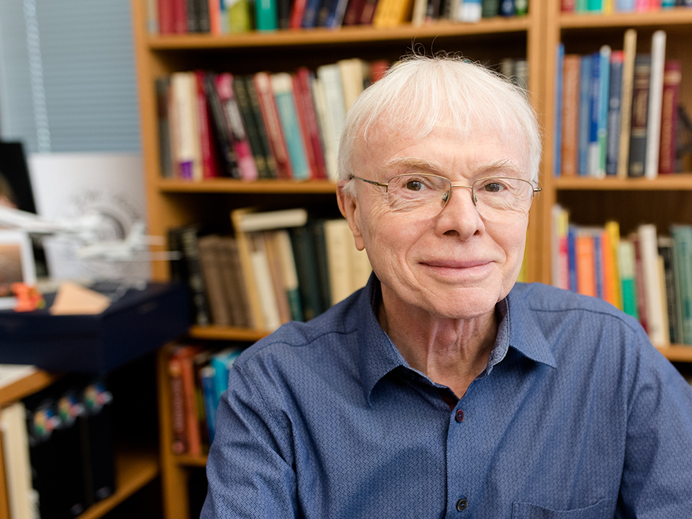 Thomas Hughes smiling in front of bookcases.