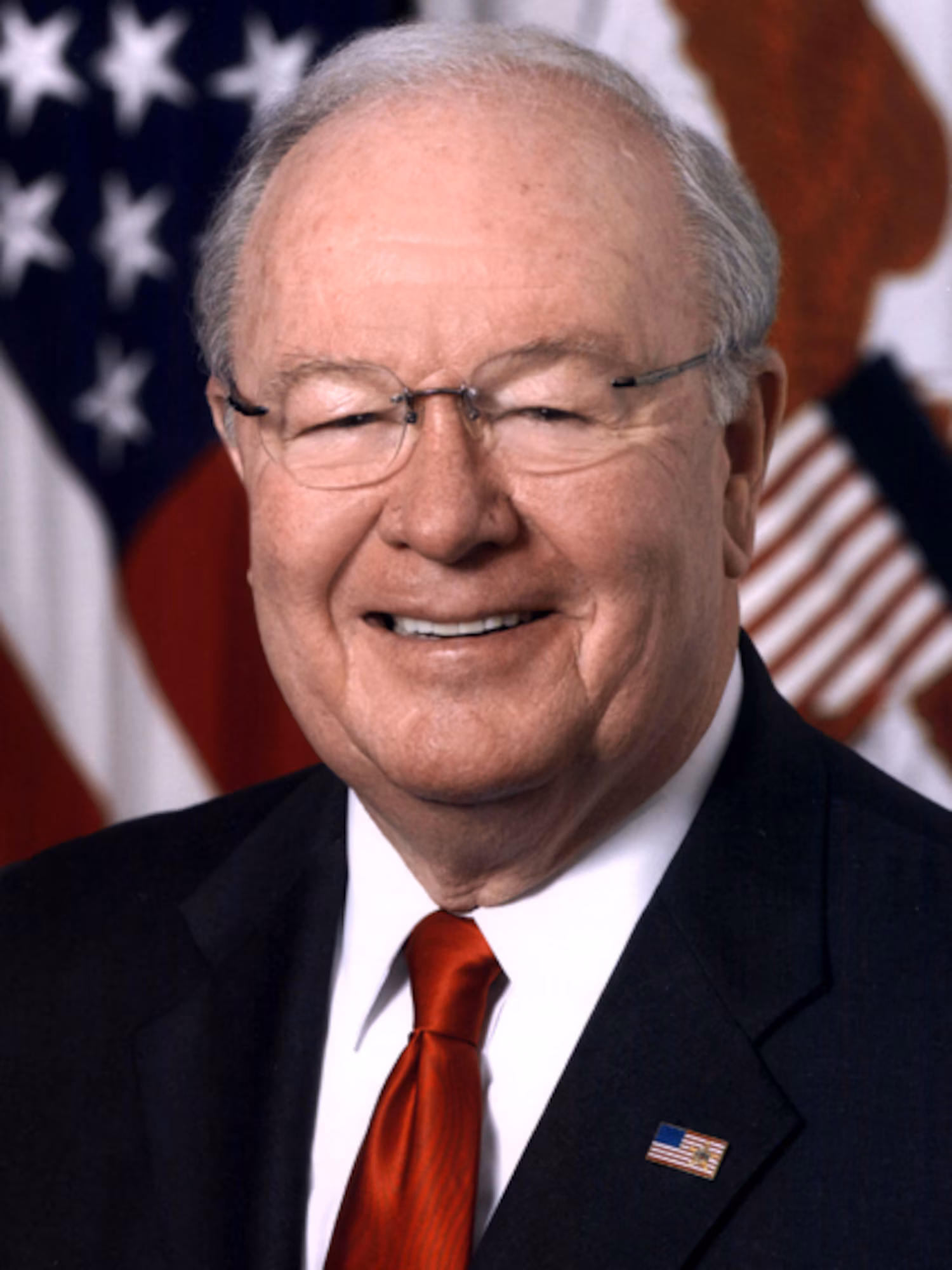 Alumnus Charles McQueary smiling in front of U.S. flag.