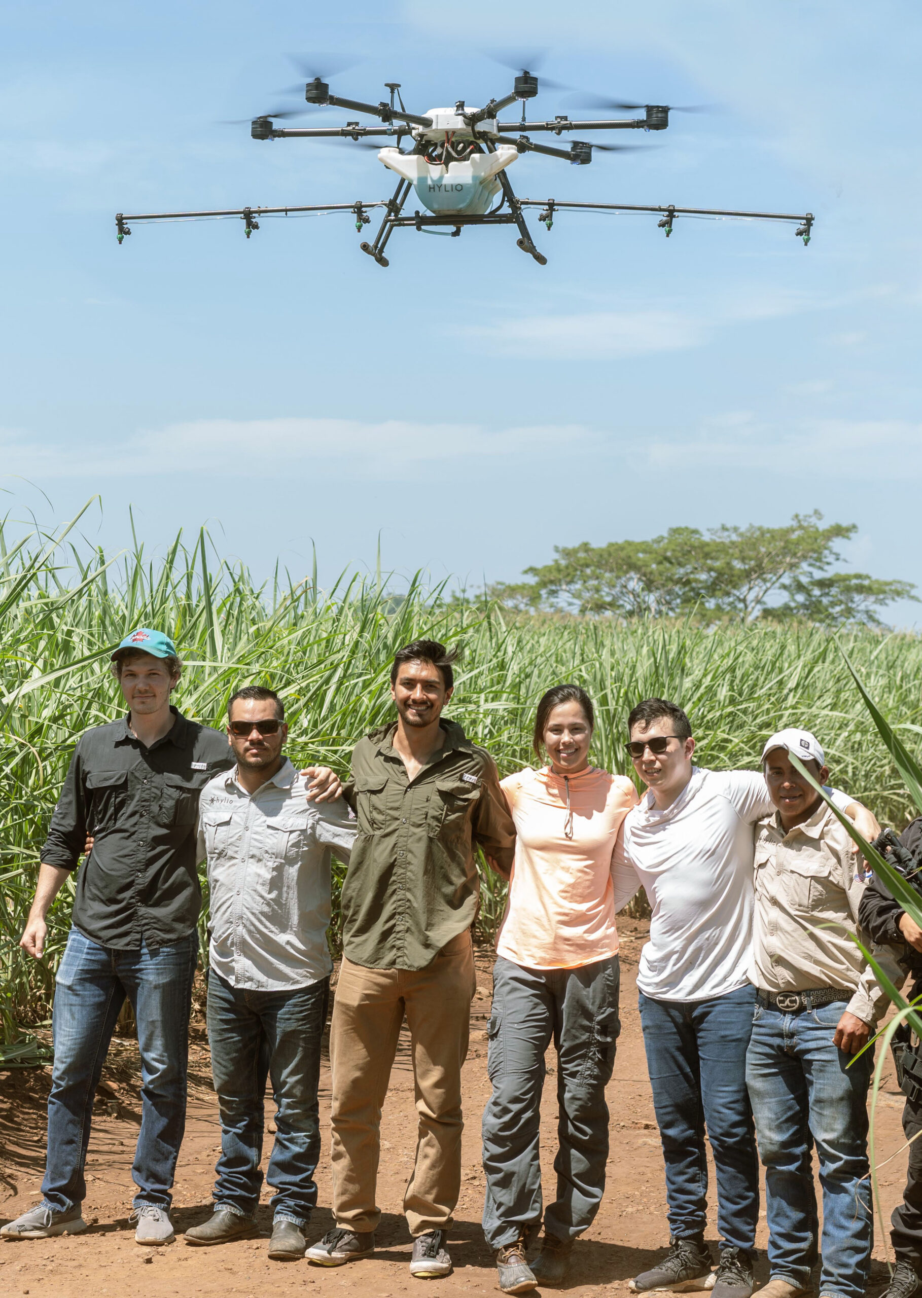 Hylio team members with drone flying overhead