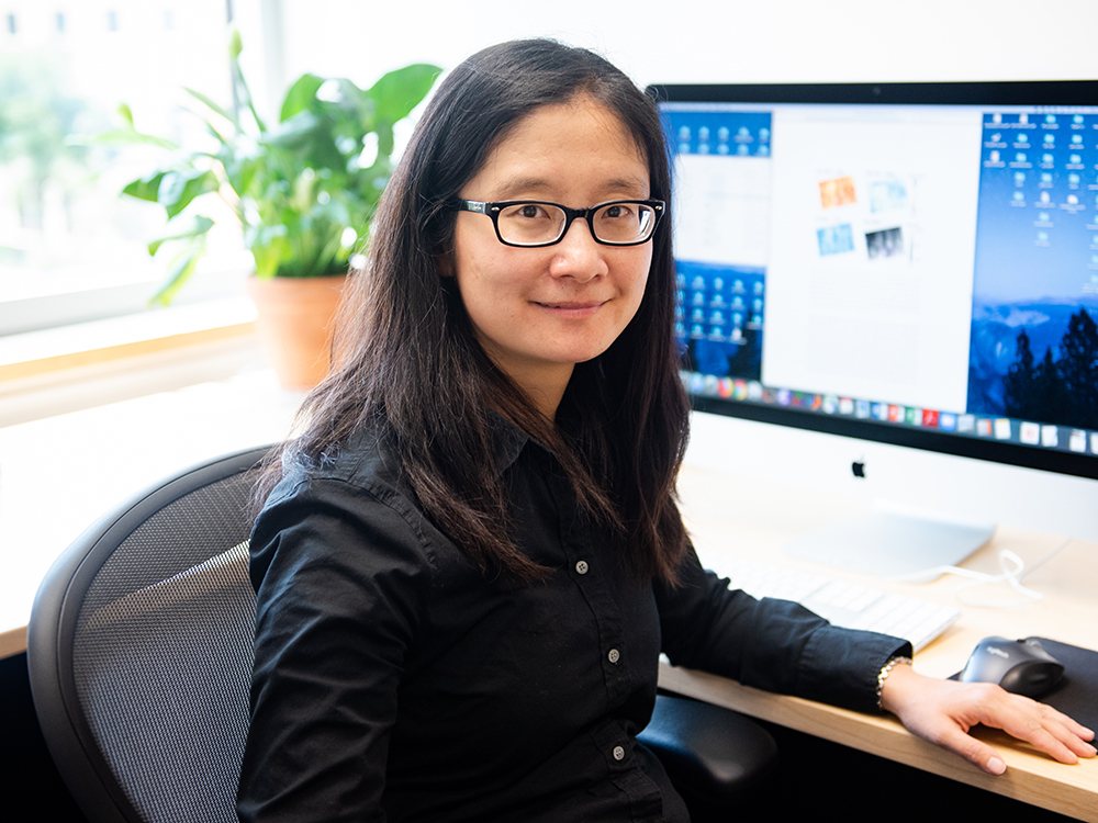 Jingyi "Ann" Chen sitting at her desk in front of a computer monitor.