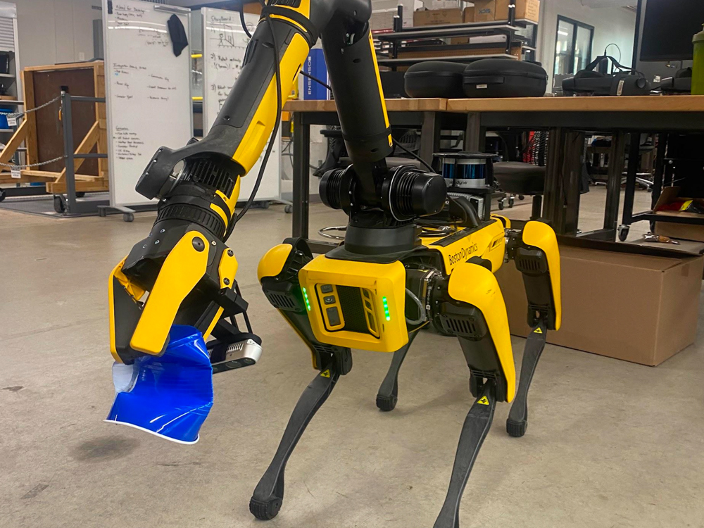 photo of Spot the robot picking up trash