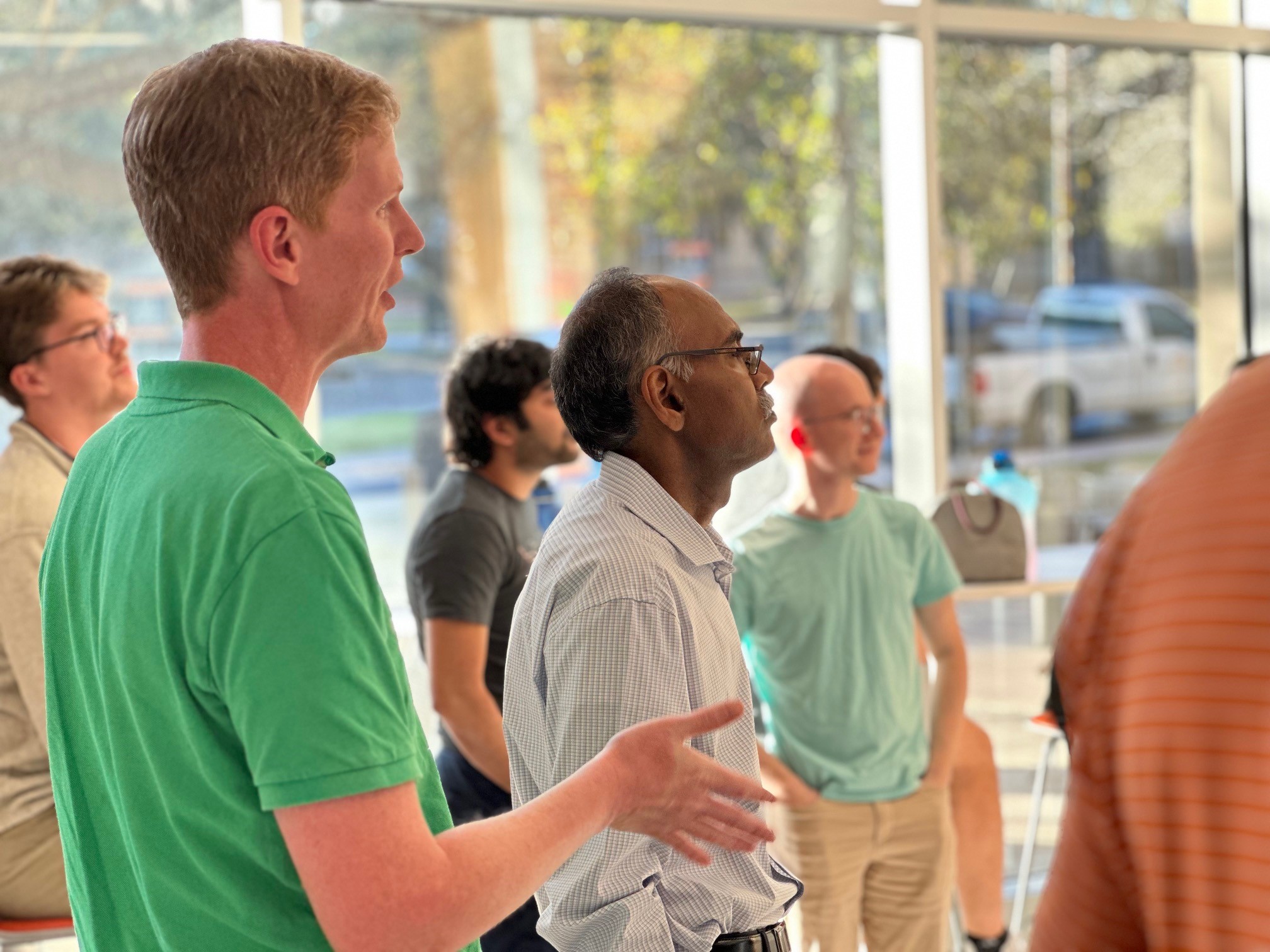 Photo of aerospace engineering faculty members Maruthi Akella and Brandon Jones watch the landing with a group of colleagues and students.