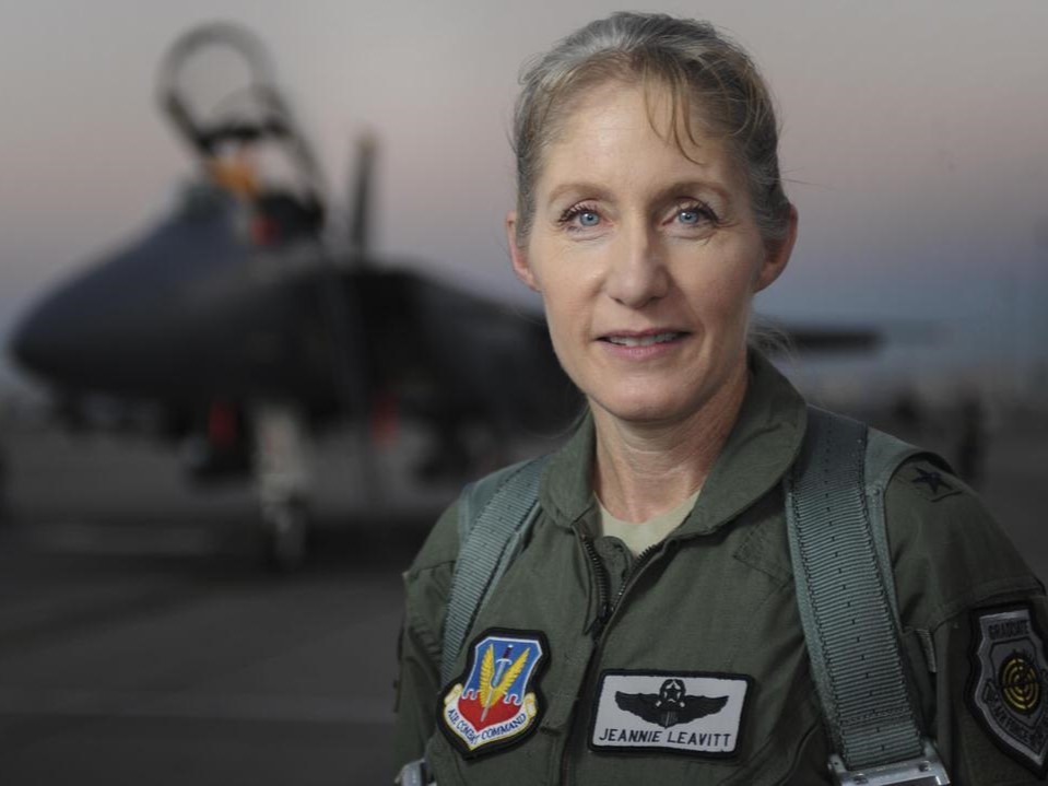 Jeannie Leavitt in flight suit with figher jet in background