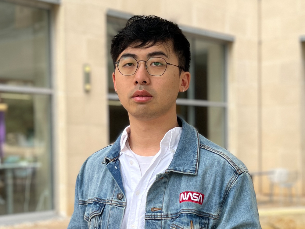 Aerospace engineering Ph.D. student Wenkai Qin in front of ASE Building