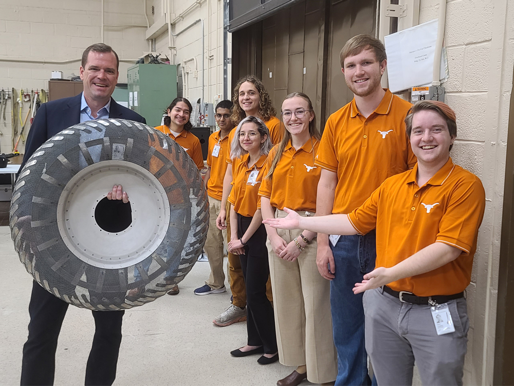 students in orange shirts standing next to Dr. Glenn