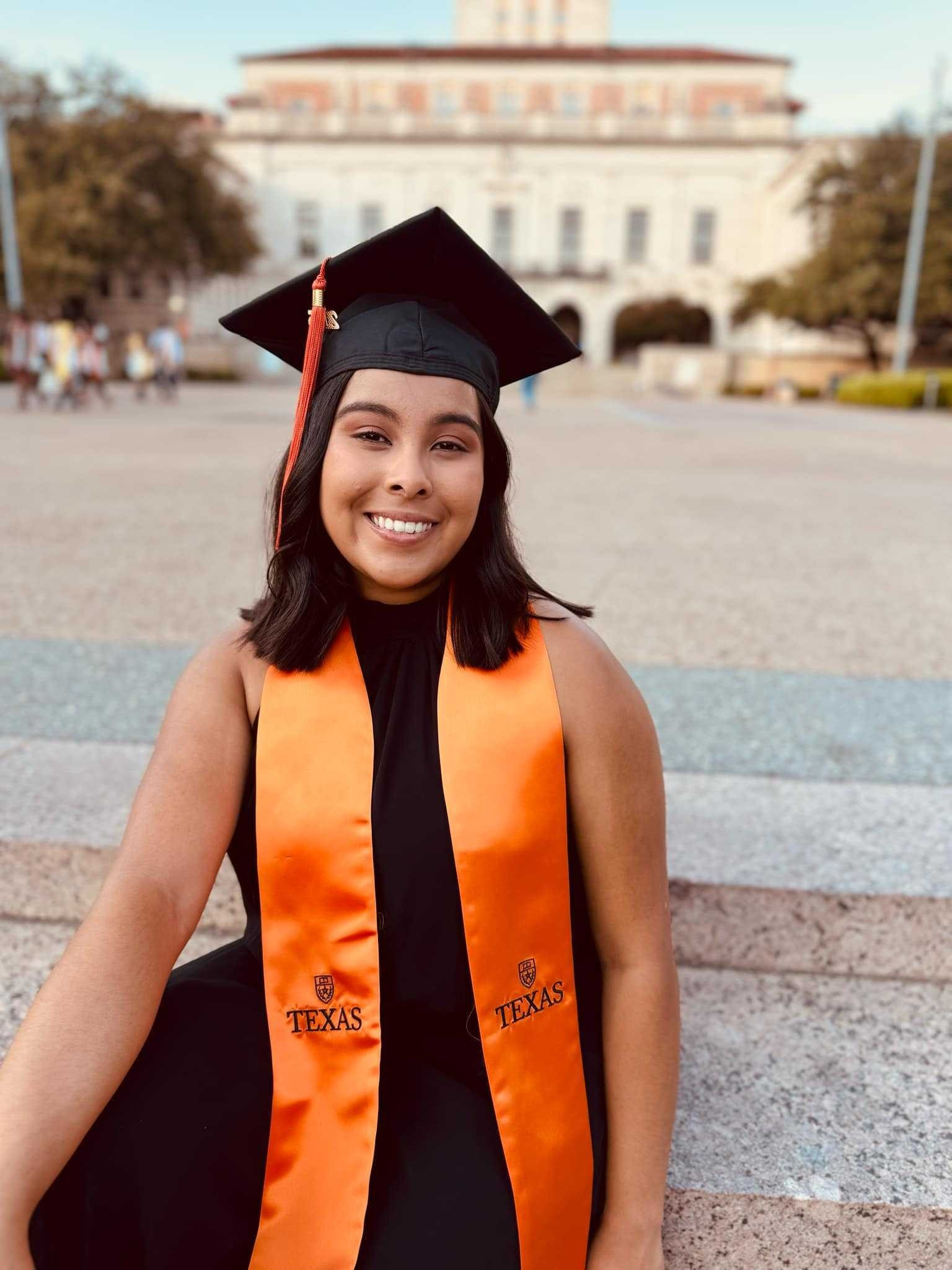 Texas Engineering student Maritza Miranda wearing graduation regalia and smiling in front of UT Tower