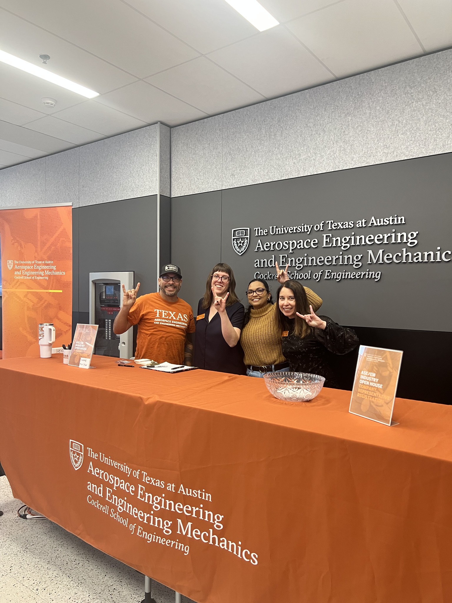 ASE/EM staff smiling behind table at Industry Open House event.