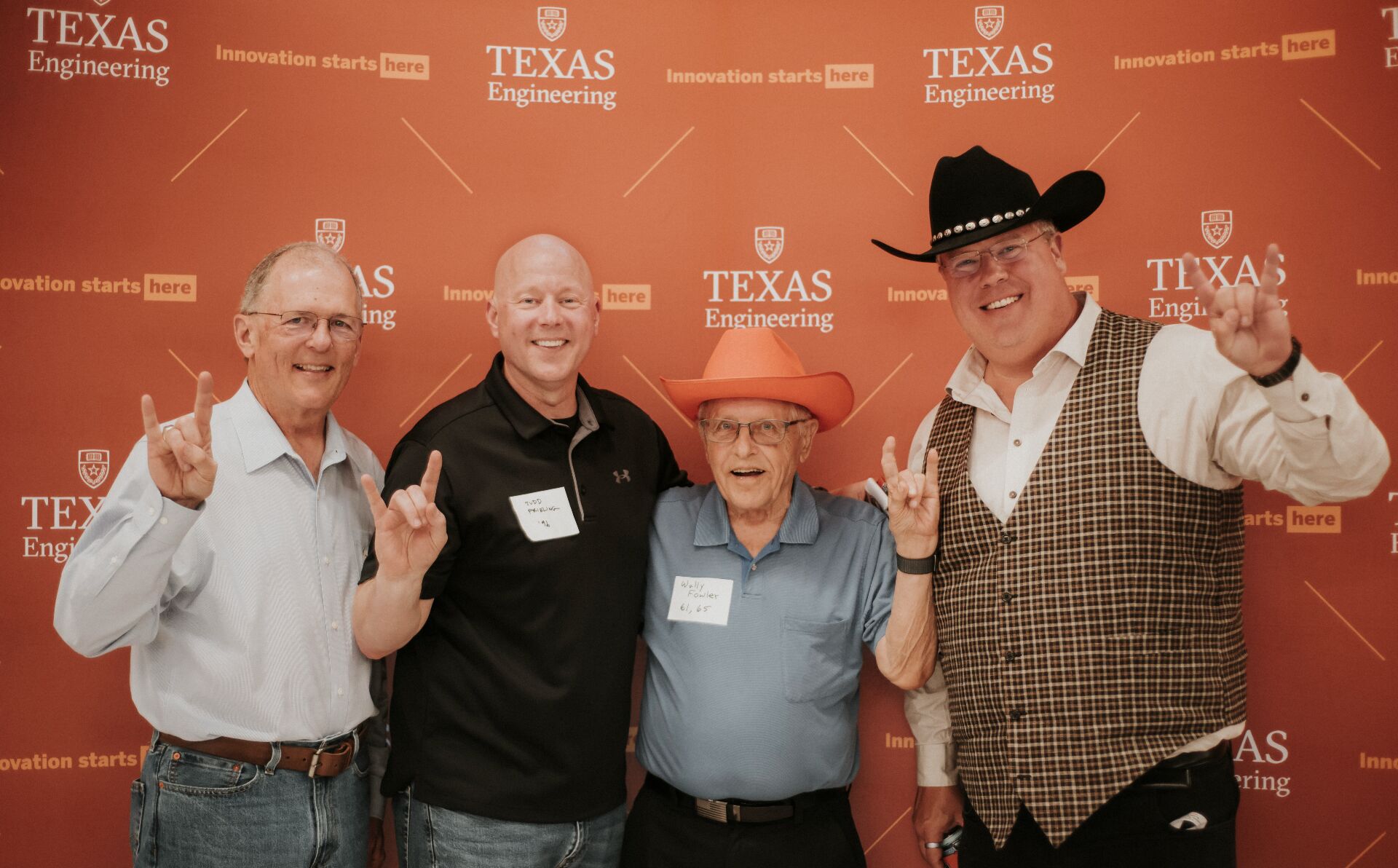 Alumni, including Tim Crain, smiling in front of burnt orange backdrop.