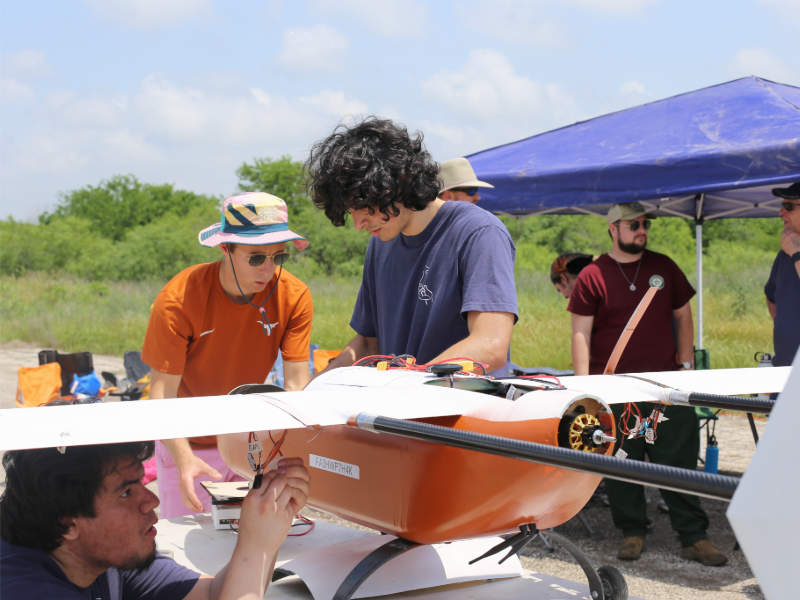 Students working on drone prototype in open field