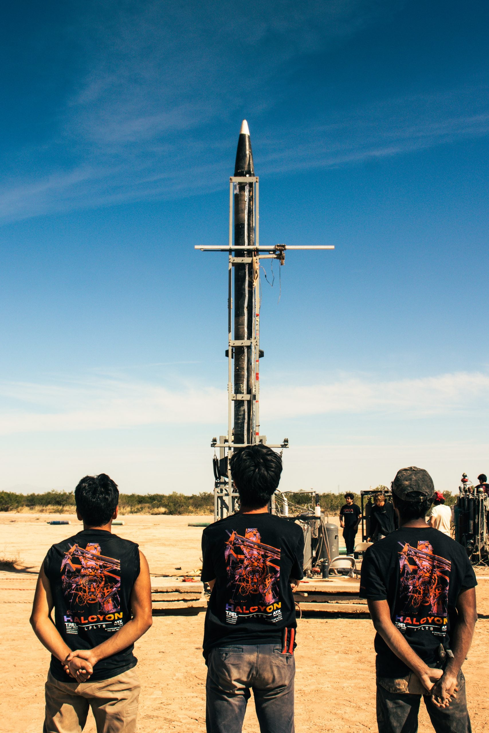Three students looking at rocket