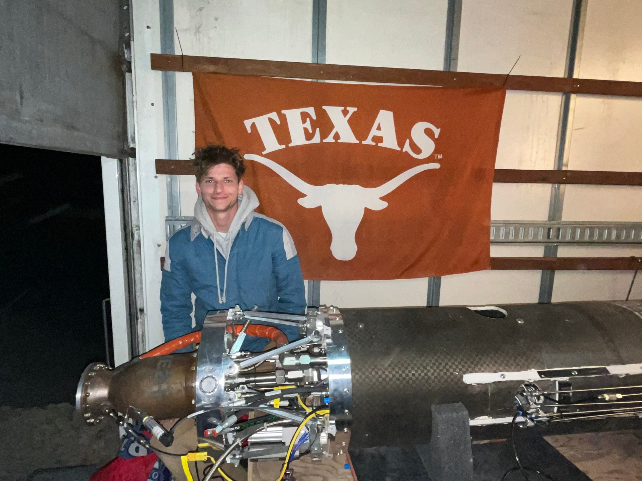 Man posing with rocket parts with the UT flag