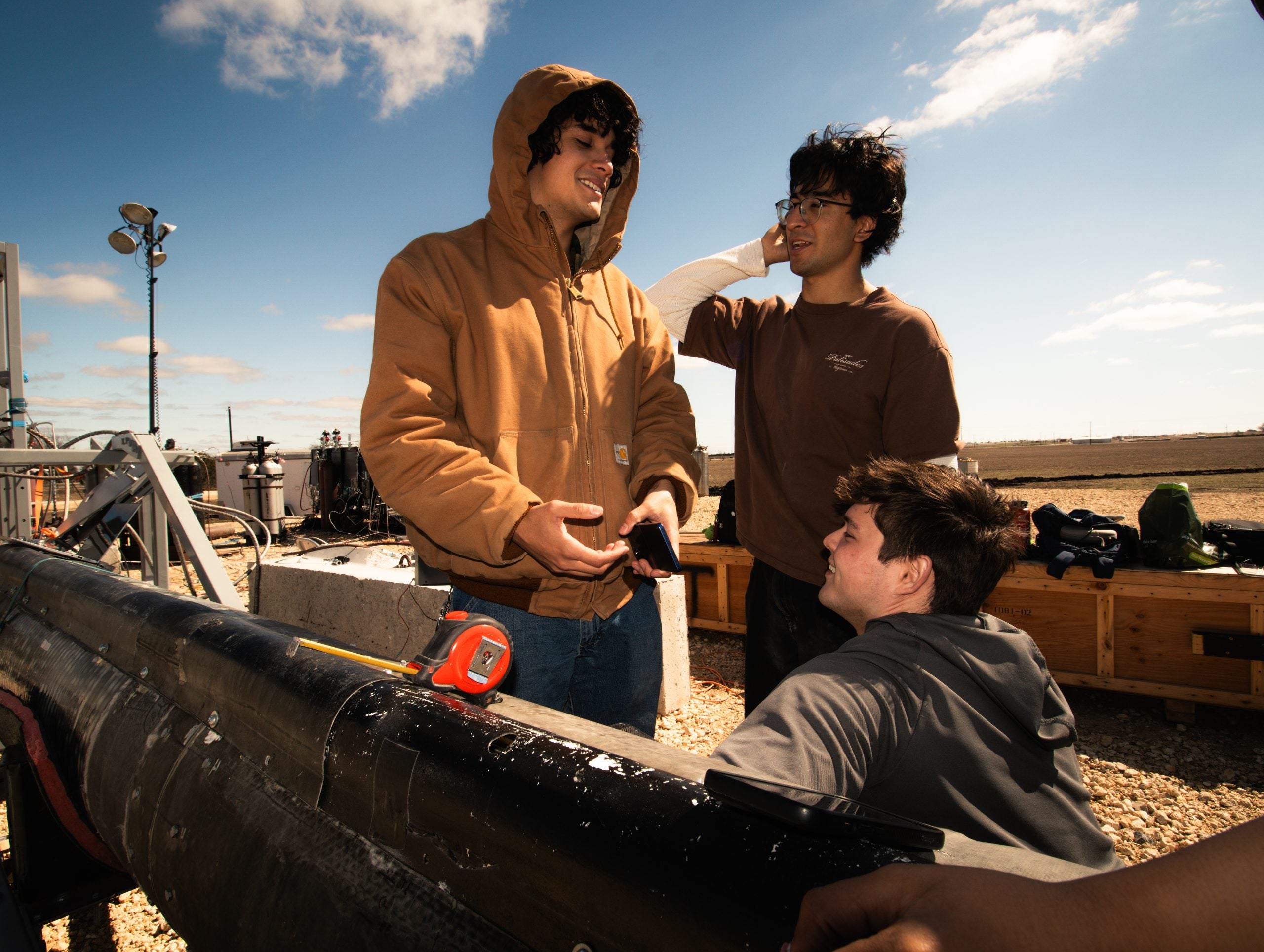 Three students talking at launch site