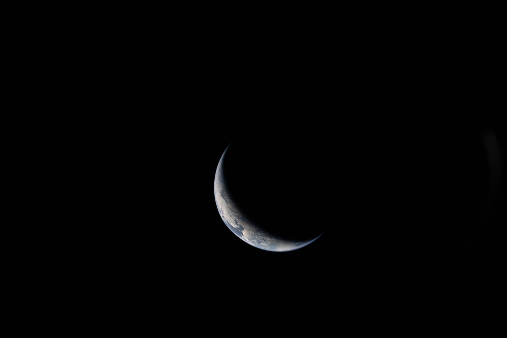 A sliver of Earth is illuminated against the blackness of space