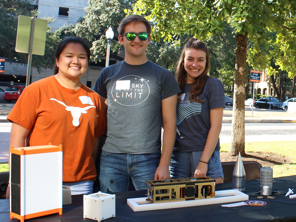 Students smiling together in front of table during welcome event.